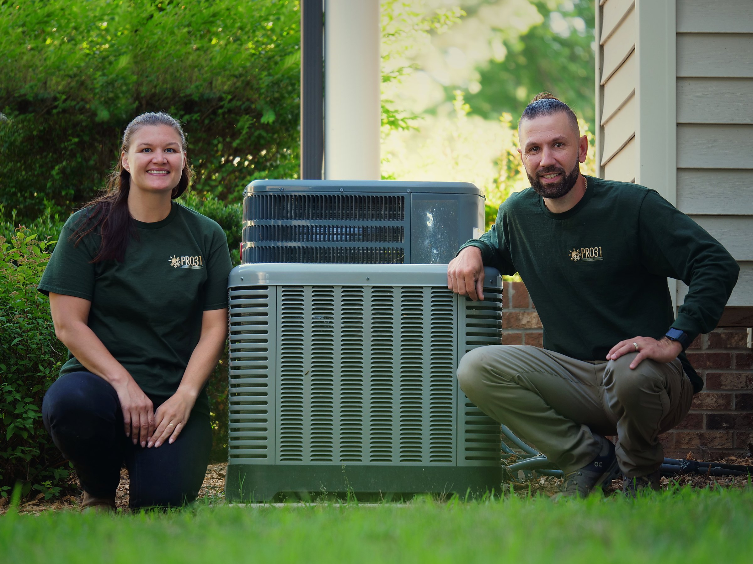 Rachelle and Ighor Martins, founders of PRO31 Heating and Cooling, beside an outdoor HVAC condenser