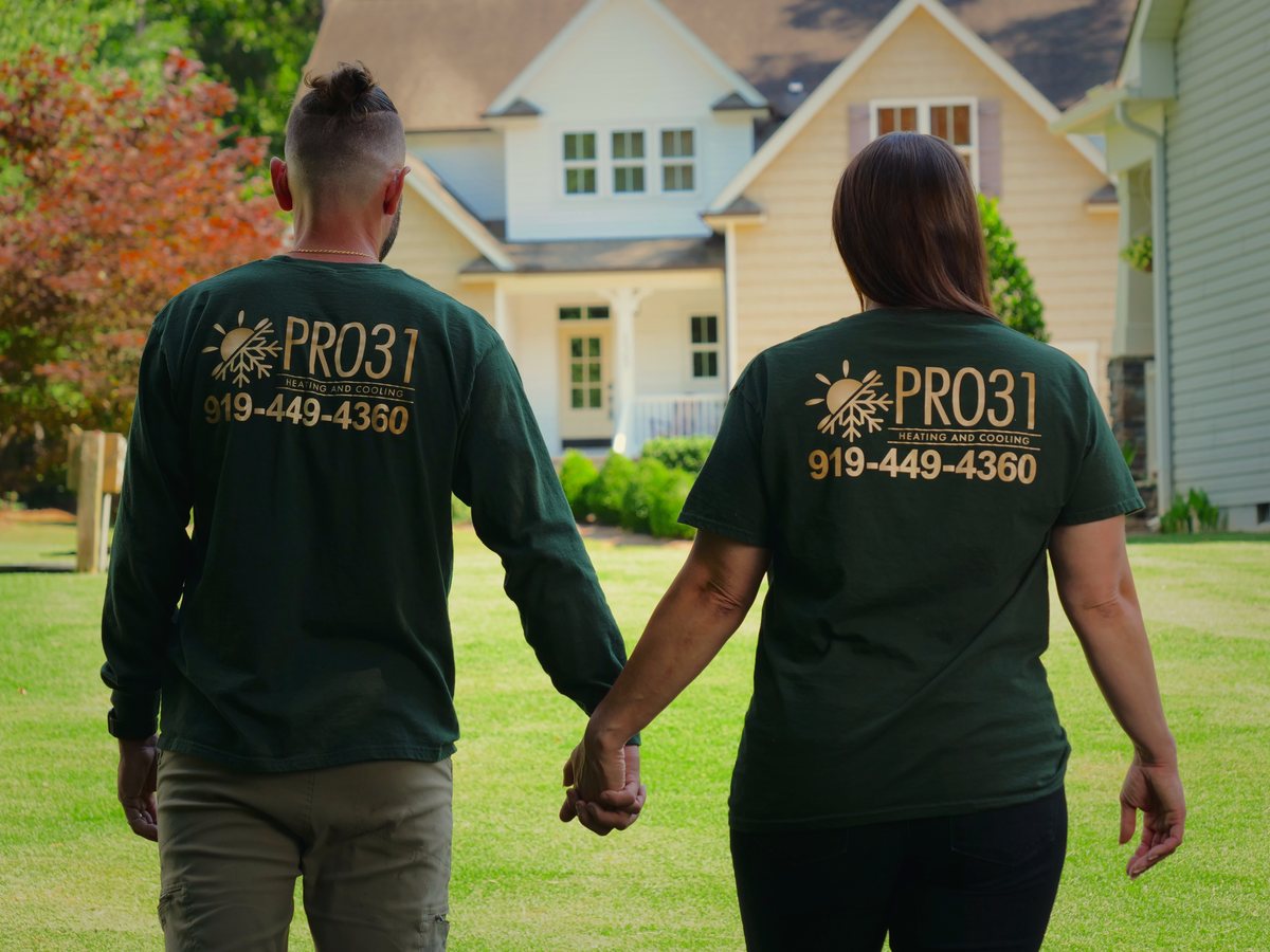 Rachelle and Ighor walking together to a home, branded shirts showing the PRO31 logo and phone number