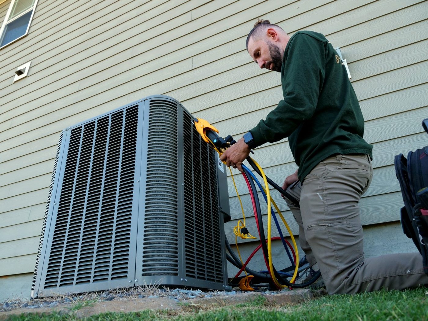 Ighor running gauges on an outdoor HVAC unit during a maintenance visit