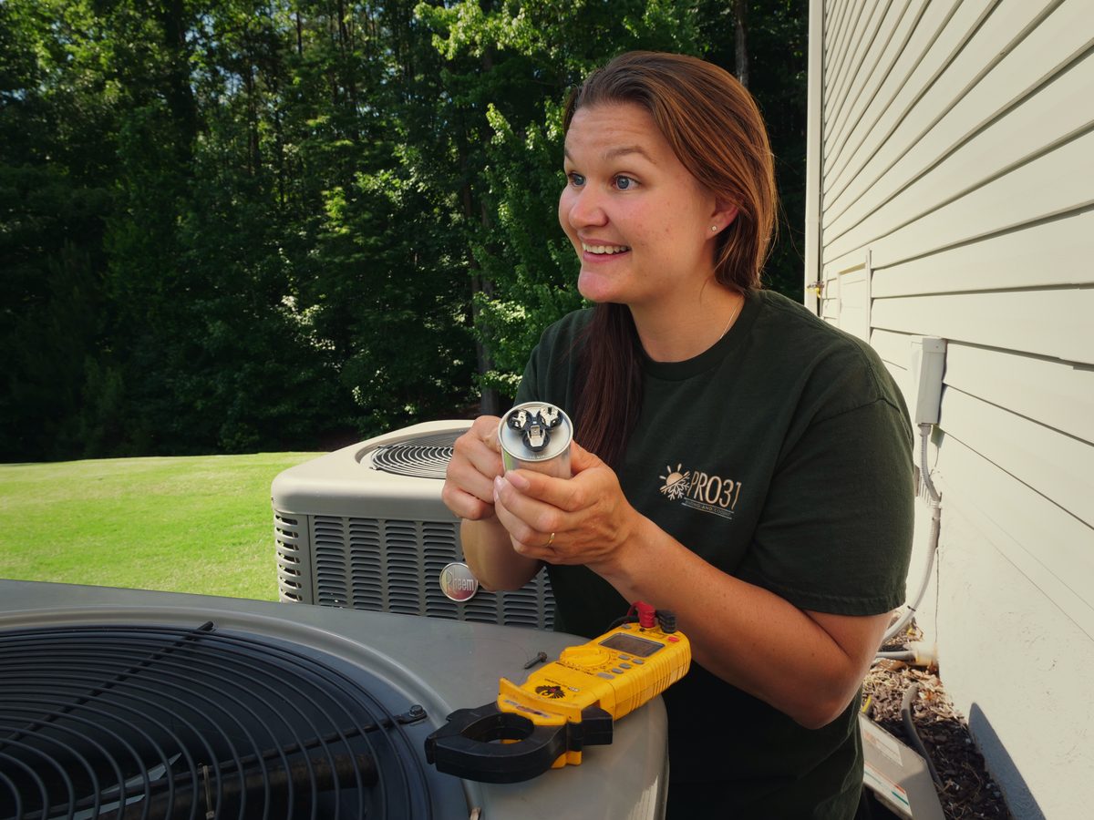 Rachelle smiling while diagnosing a capacitor on an outdoor unit